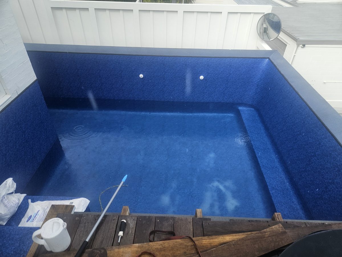 A small rectangular pool with a dark blue liner and a built-in step along one side