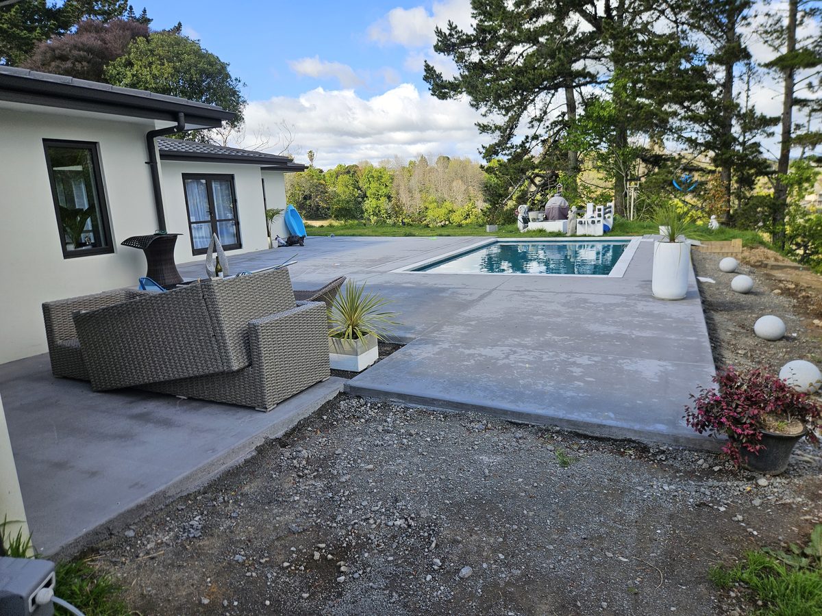 A rectangular pool in a wide concrete surround with outdoor sofas on the patio