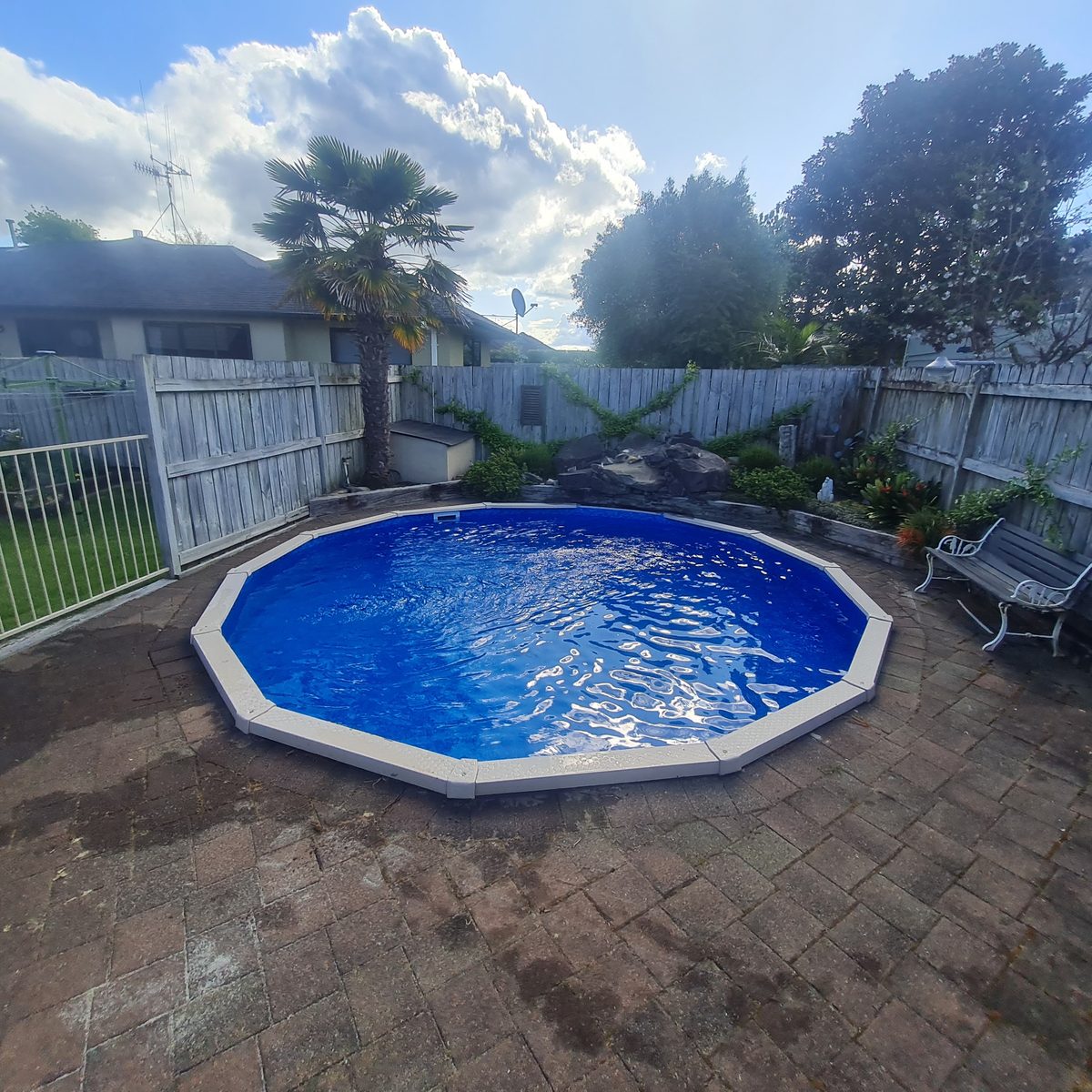 A round pool with sparkling blue water set into a paved courtyard