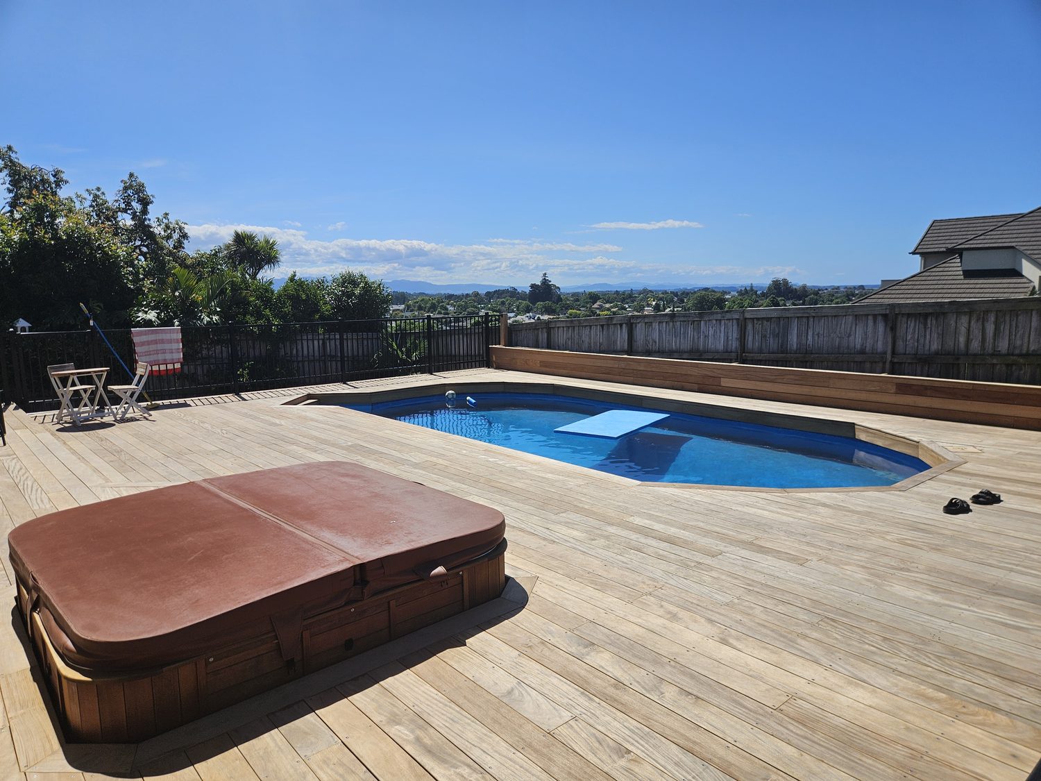 A large timber deck with a swimming pool built into it in Tauranga, with a spa beside it