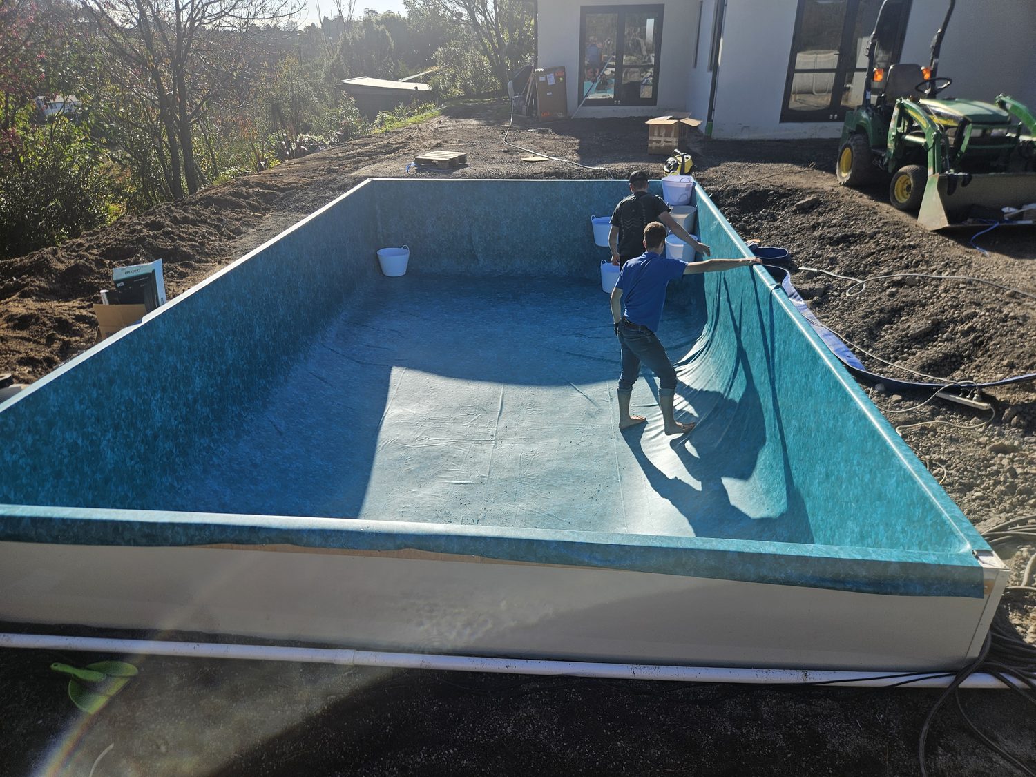 Two men fitting the liner in a new rectangular pool