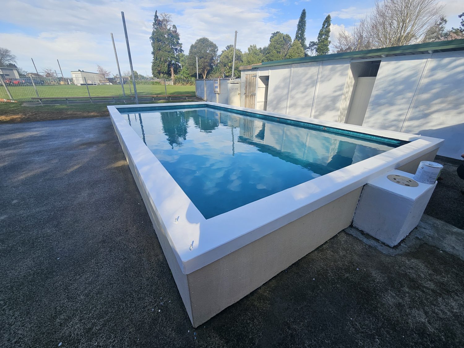 A raised rectangular pool with a white surround, newly filled