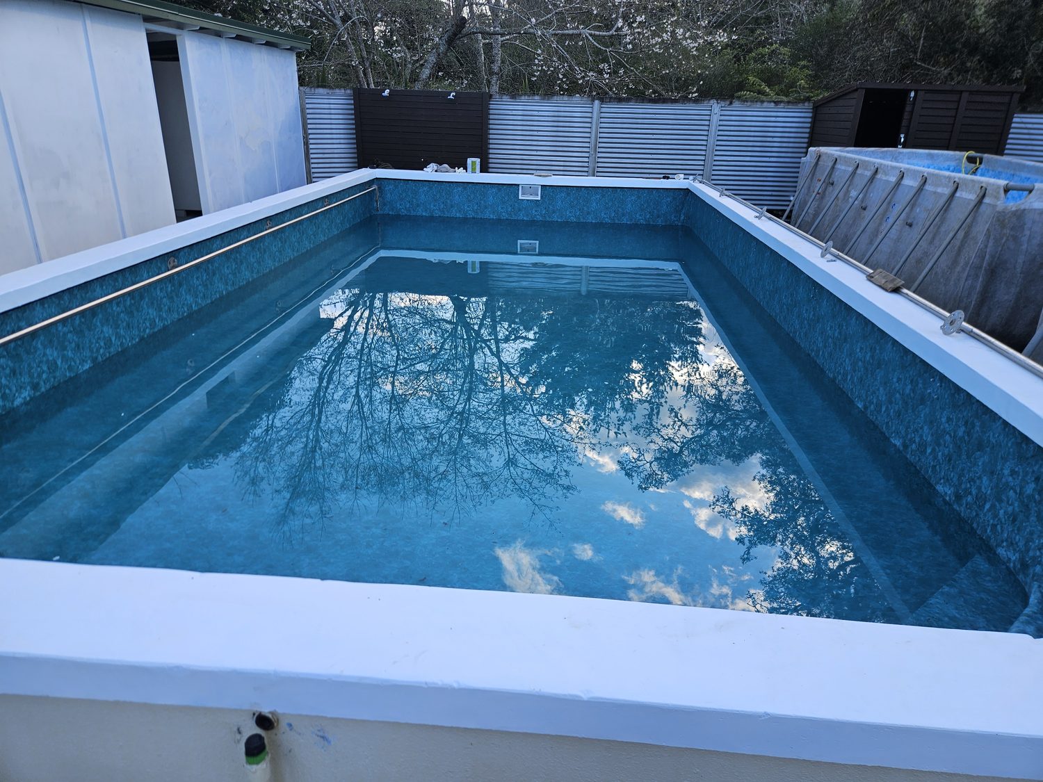 A raised rectangular pool with a white coping and a patterned blue liner