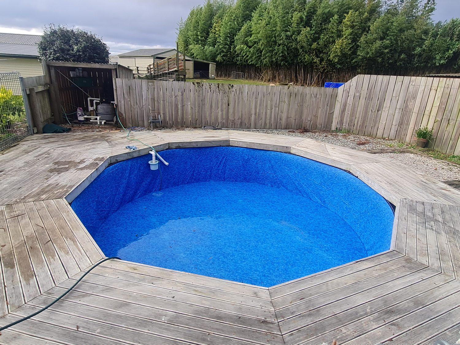 A round pool with a patterned blue liner set into a weathered timber deck