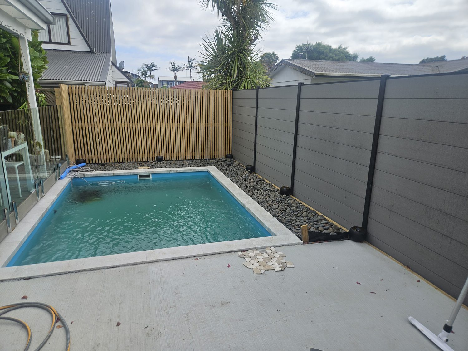 A small rectangular pool in a courtyard with a slatted fence