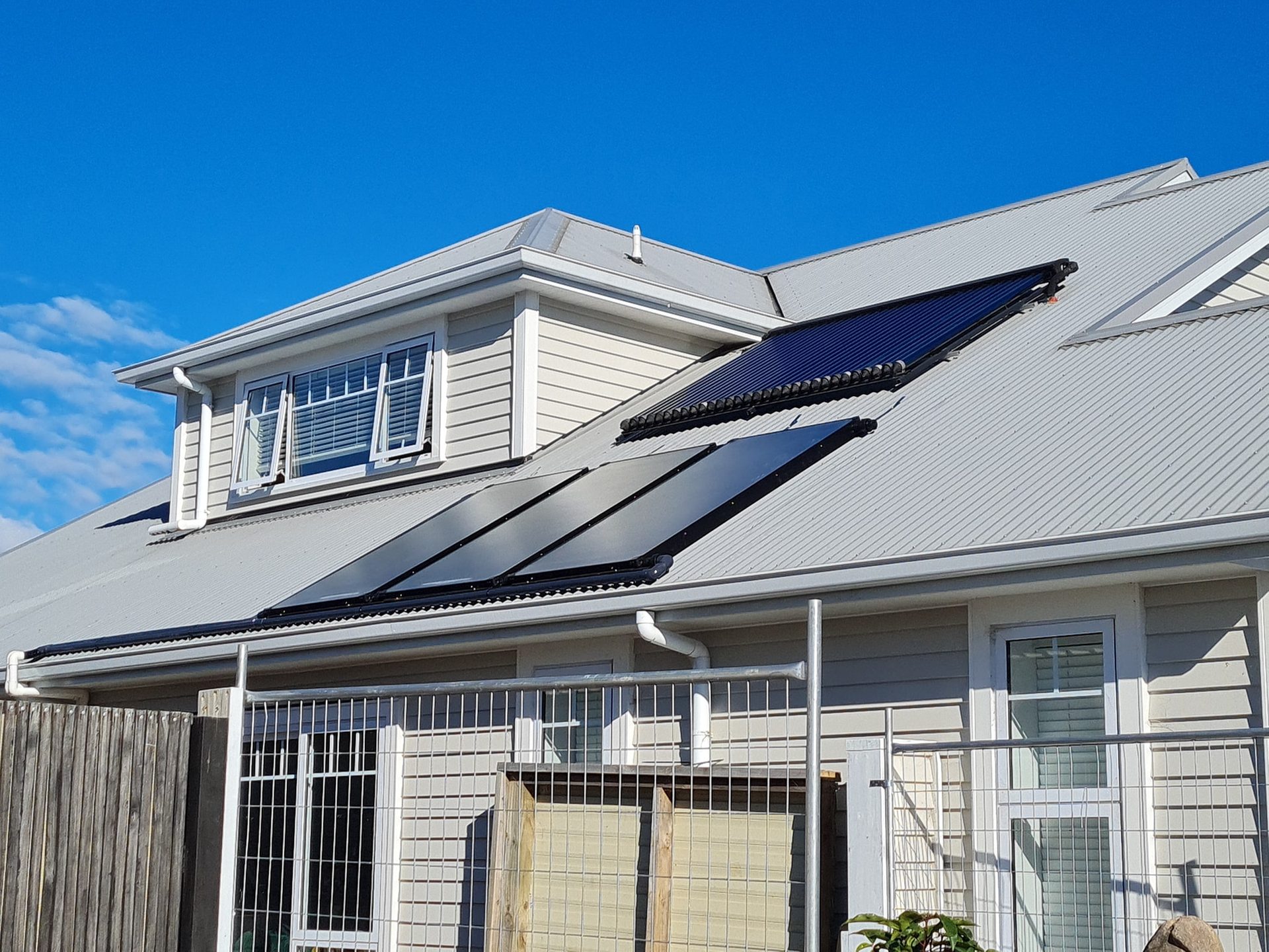 Solar panels on the roof of a weatherboard house under a clear blue sky